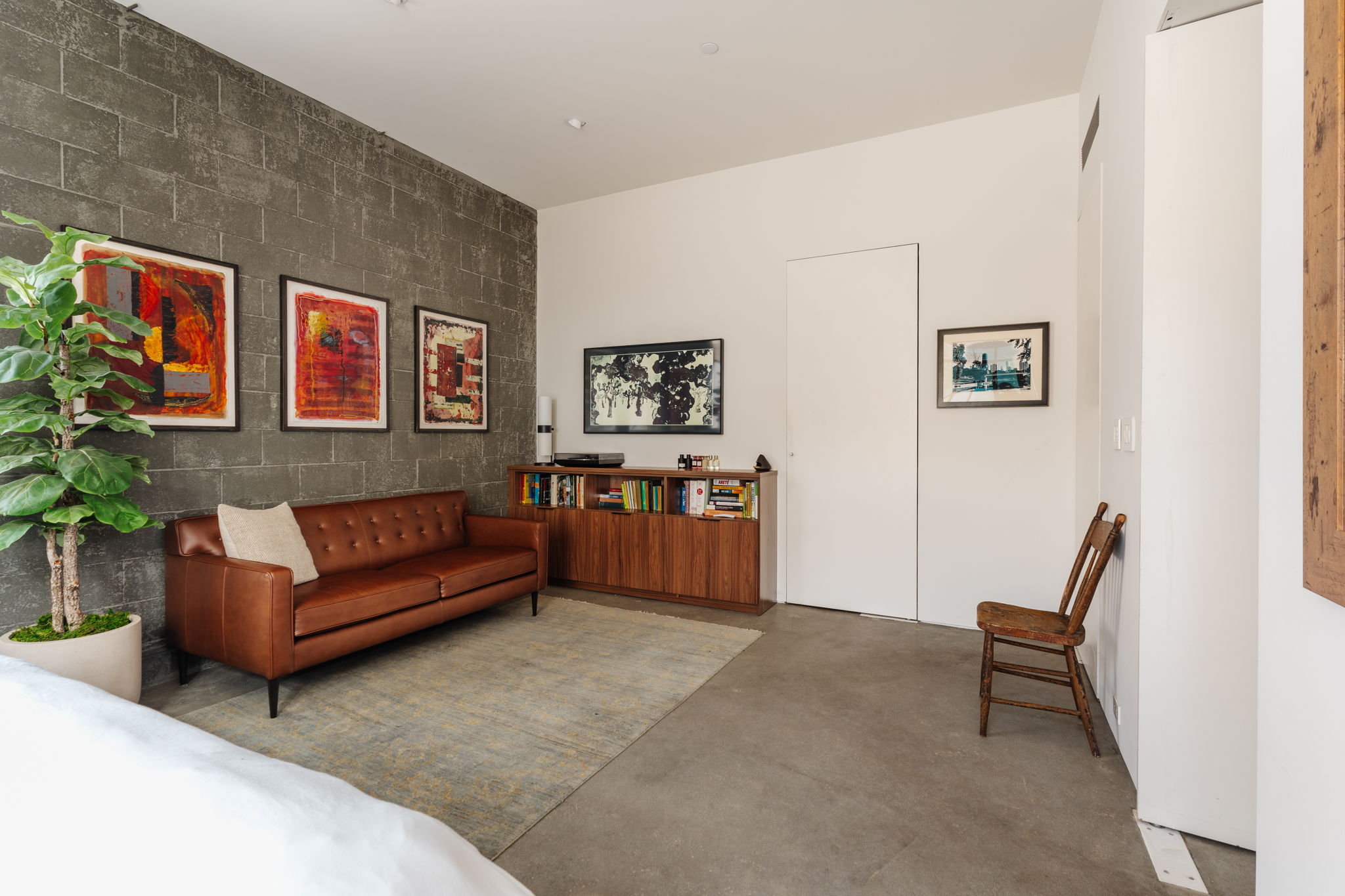 Loft bedroom wall with two untitled 2004 black and white drawings by Anna Rac and colorful abstract art