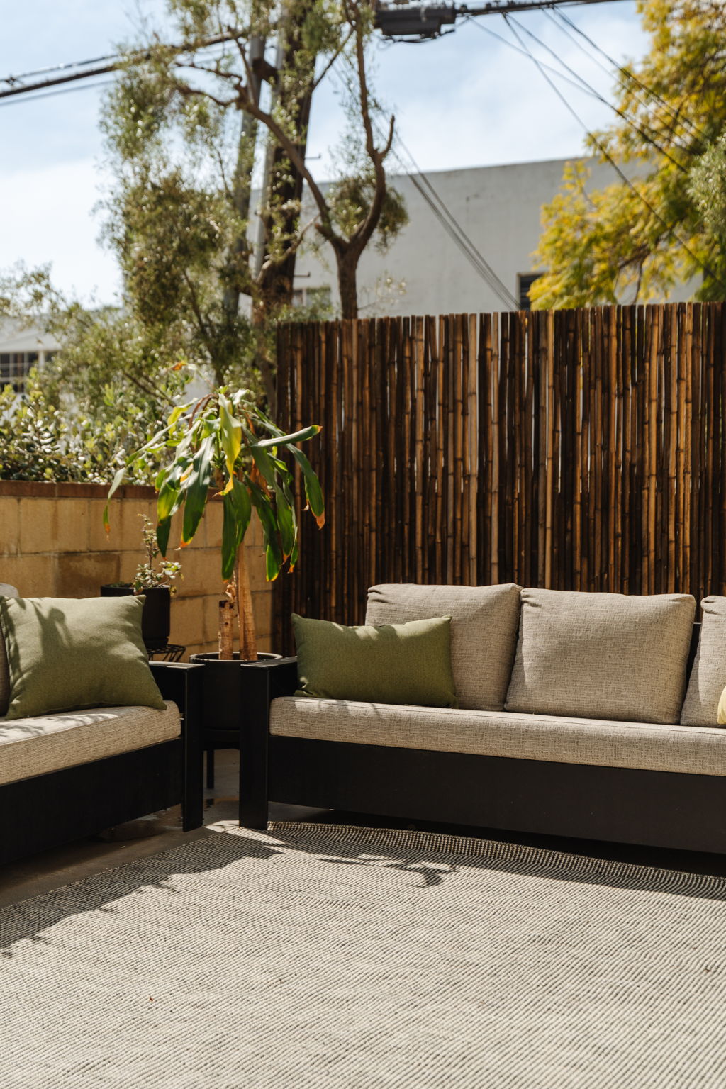 Outdoor patio seating with plants and bamboo privacy screen